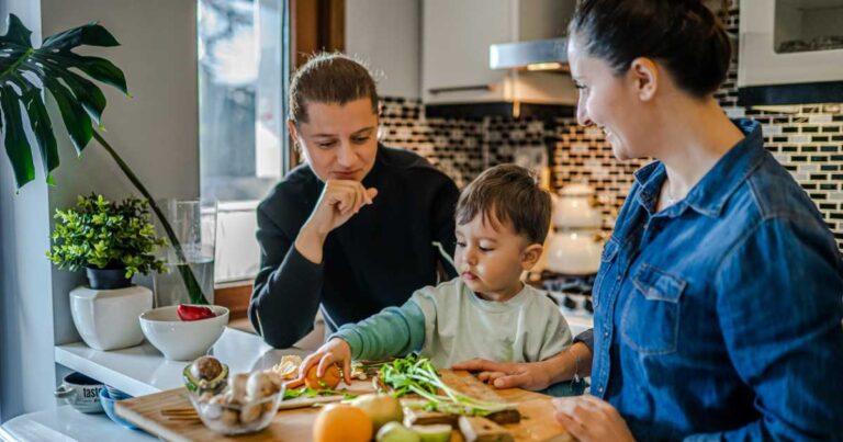 Same sex couple and their child preparing dinner in kitchen stock photo