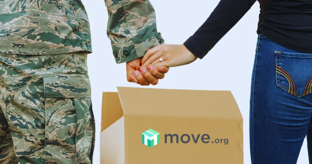 Military couple holding hands by a moving box.